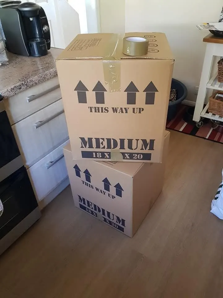 Sturdy medium removal boxes taped and marked this way up in a kitchen